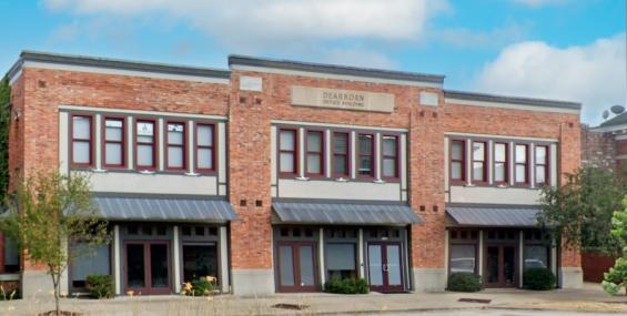 A close-up of the Dearborn Office Building within Chesterfield Mixed-Use, highlighting its symmetrical design with large second-floor windows and storefront-style entrances on the ground level. The metal awnings add a modern touch, while neatly trimmed shrubs frame the entrance.